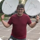 Image of man stood in-front of Sky dishes wearing a red t-shirt
