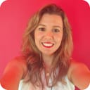 Selfie image of a women with blond hair and a white shirt against a pink background