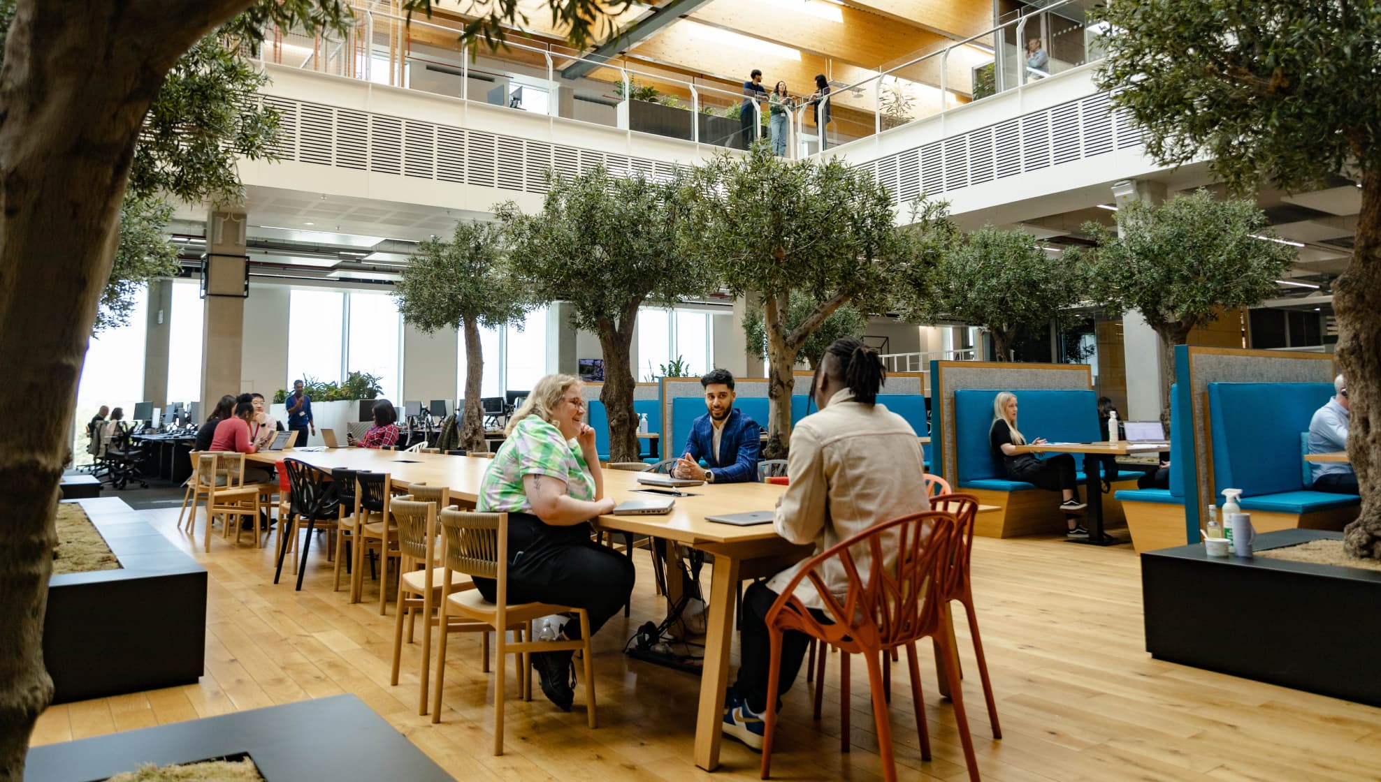 different groups of people sitting at tables in the middle of a large office space