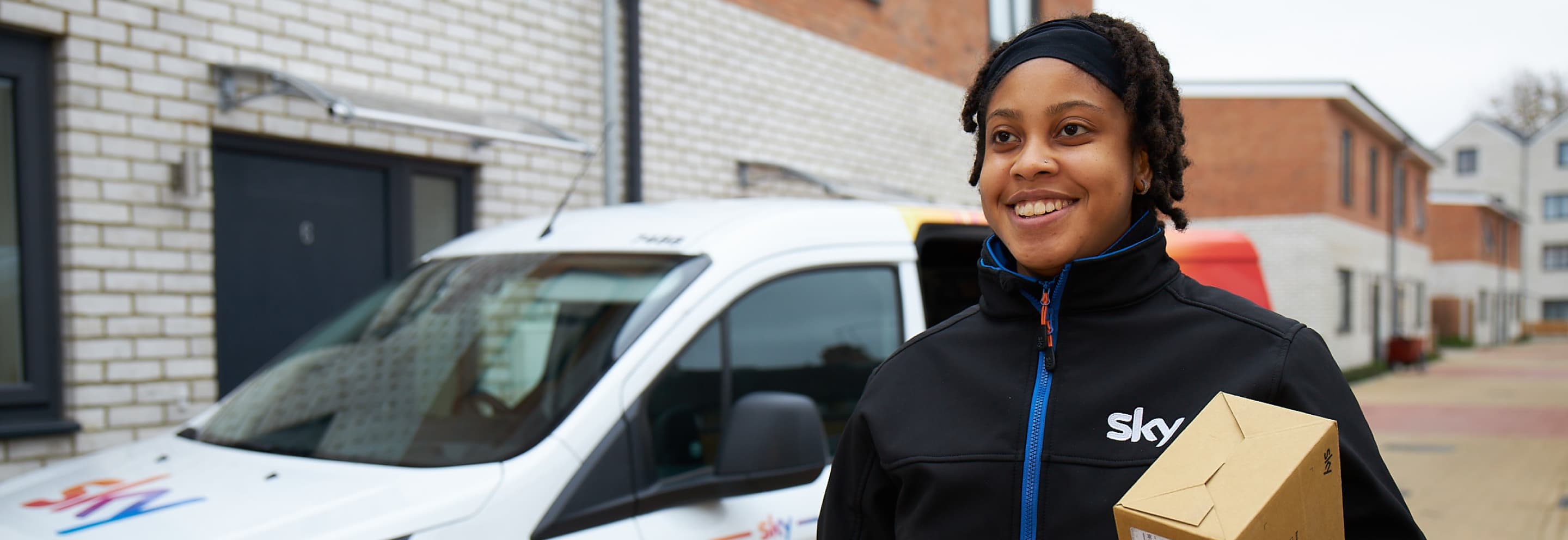 a black woman standing next to a Sky van