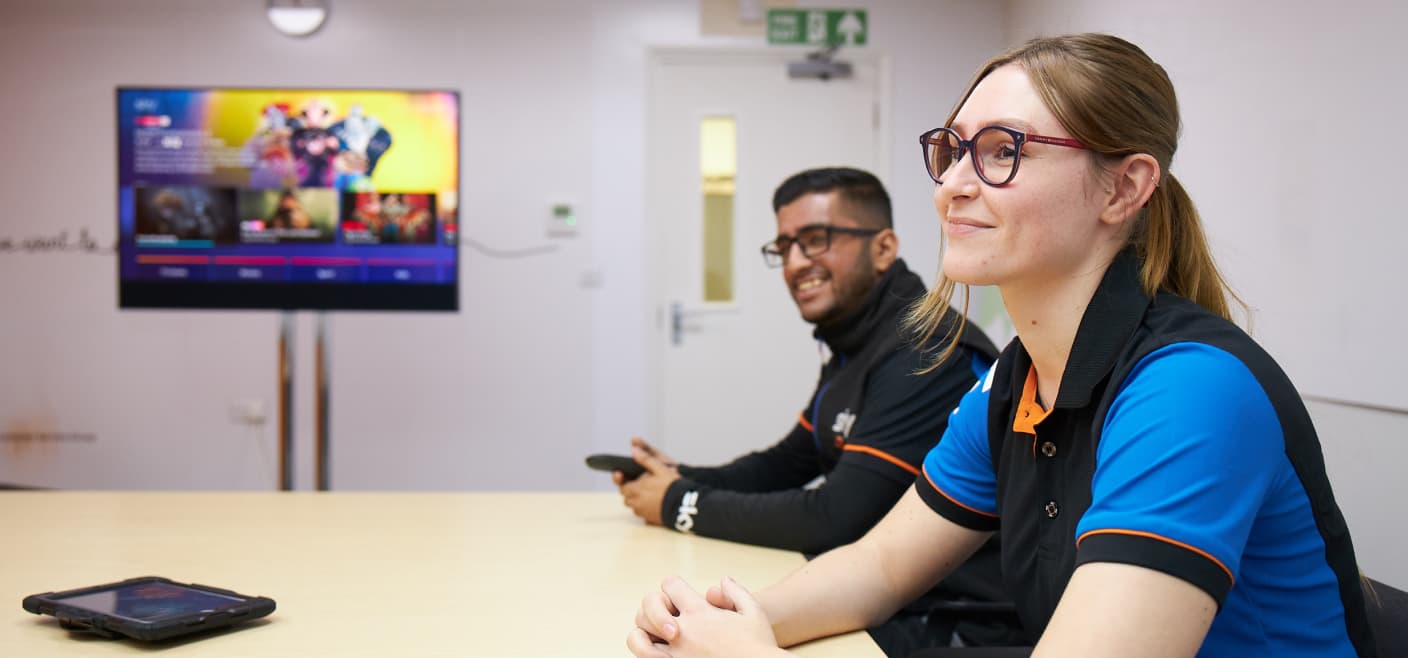 a woman in glasses sitting at a table next to a male colleague