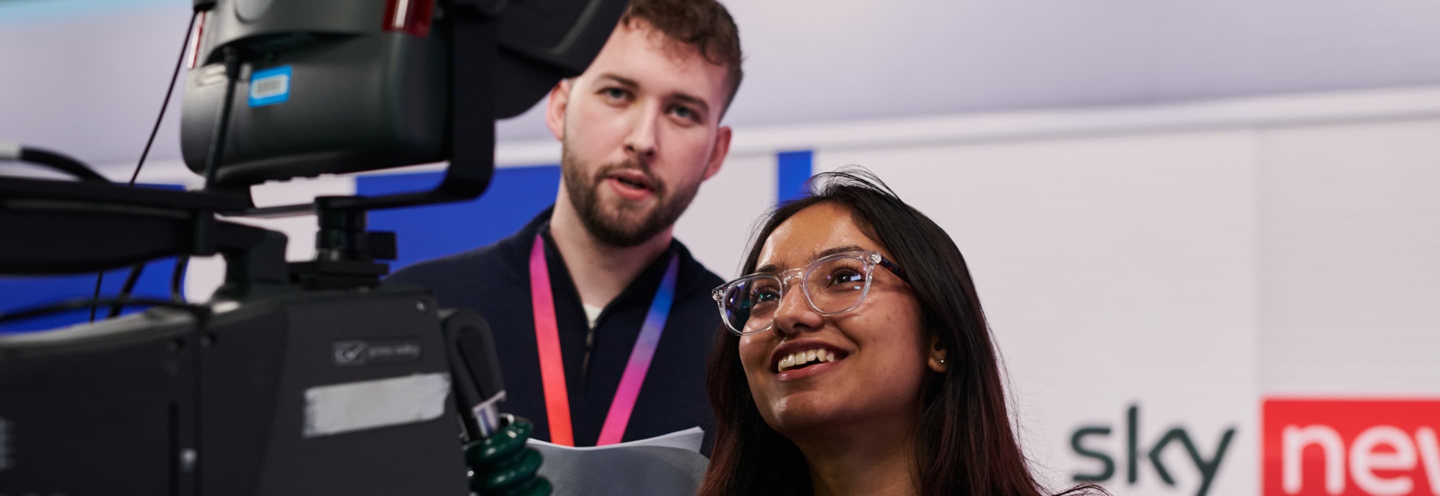 woman with glasses looking at a camera screen with male colleague