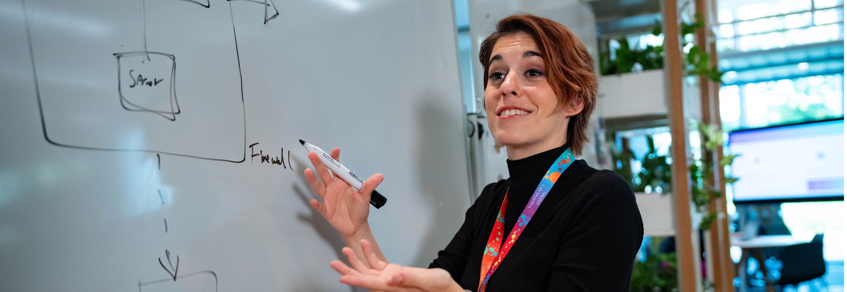 woman with short red hair writing on a whiteboard