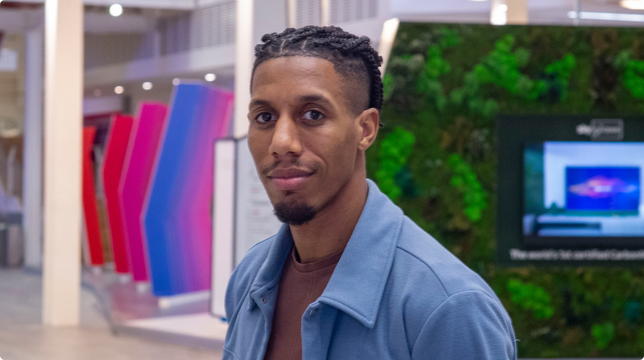 black man with tied back braids in an open blue collared shirt
