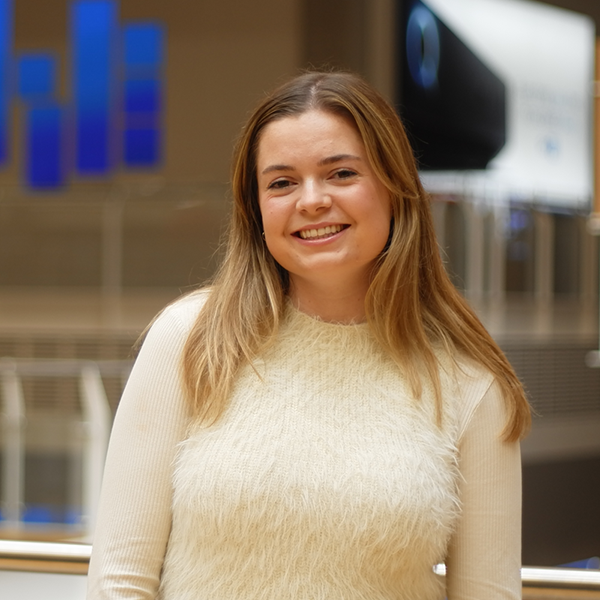 Caroline standing in front of the Sky office mezzanine. In the background is a faded banner advertising Sky Q