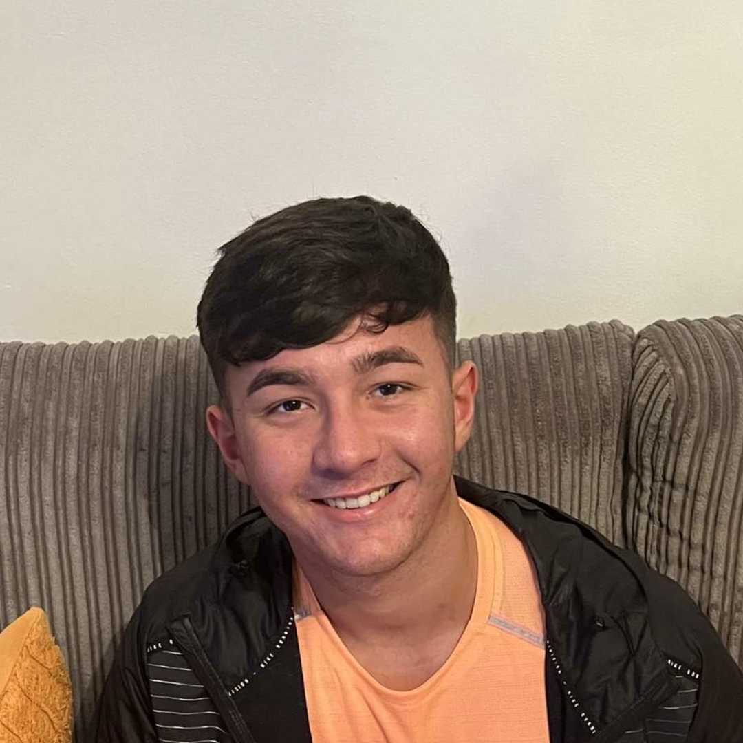 Aaron sat in a brown sofa, smiling