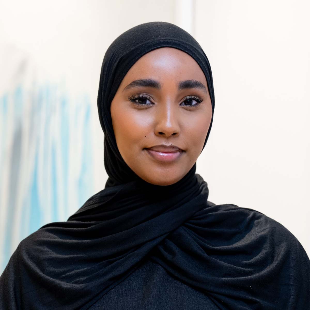 Salma, standing in front of a faded white background.