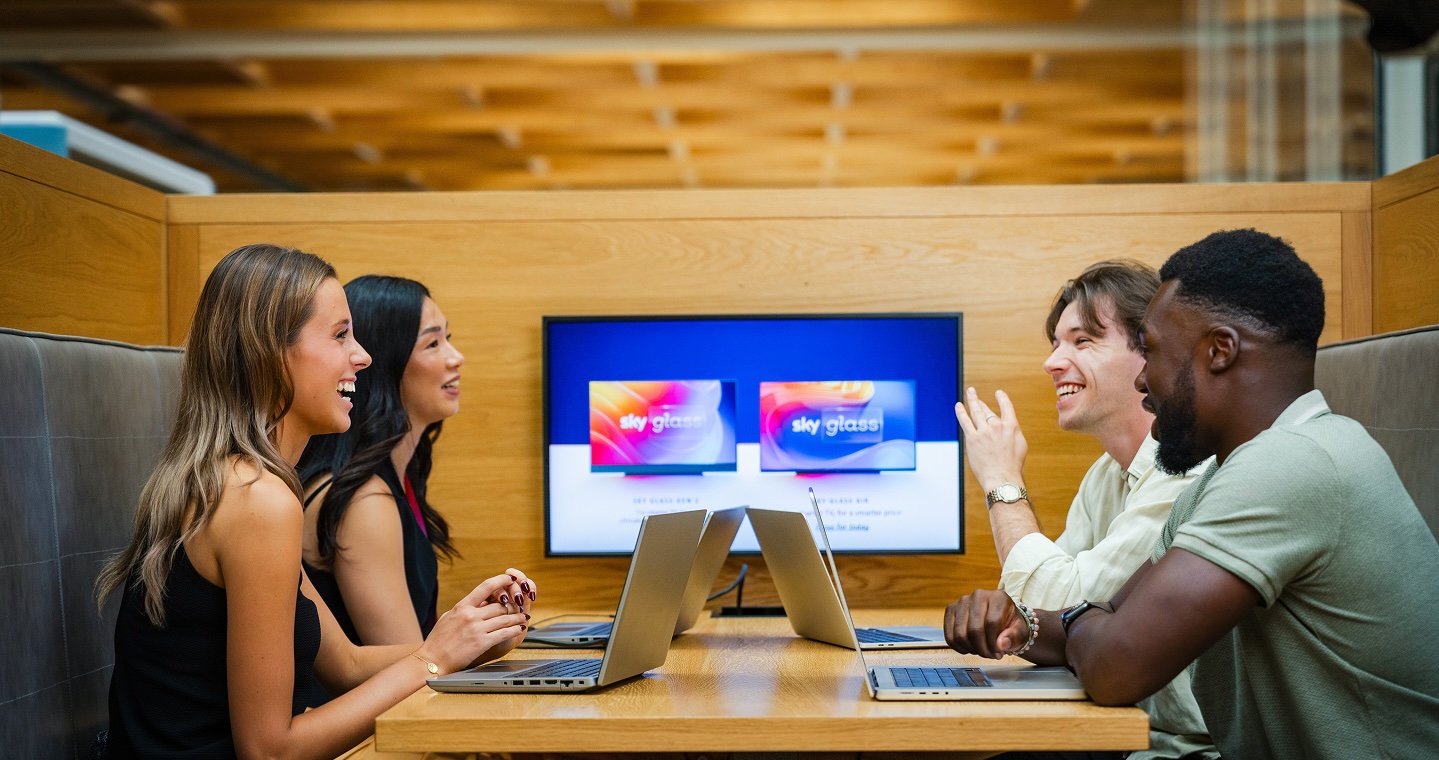 Four people sat with open laptops in an office booth
