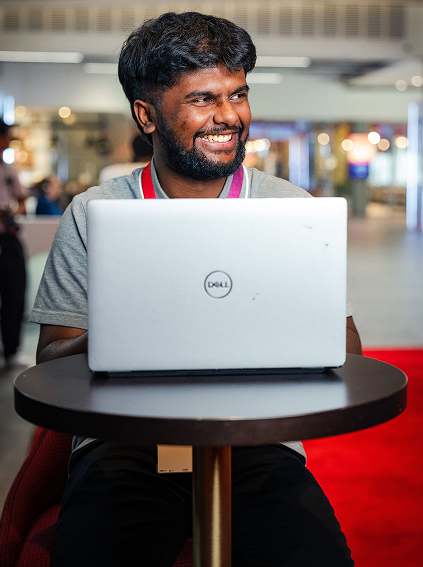 A man sitting at a table with a laptop open and smiling