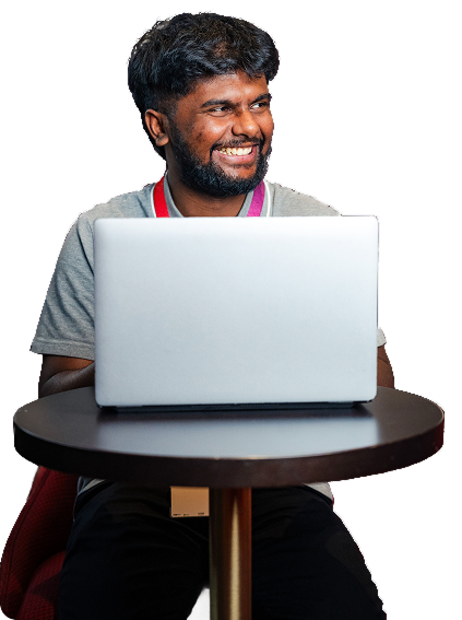 A man sitting at a table with a laptop open and smiling