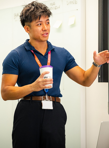A man speaking whilst holding a cup with the Sky logo on