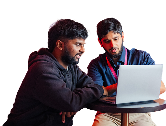 Two people working at a laptop on a small table