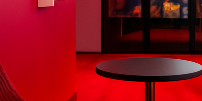 A small round dark table in a red carpeted room