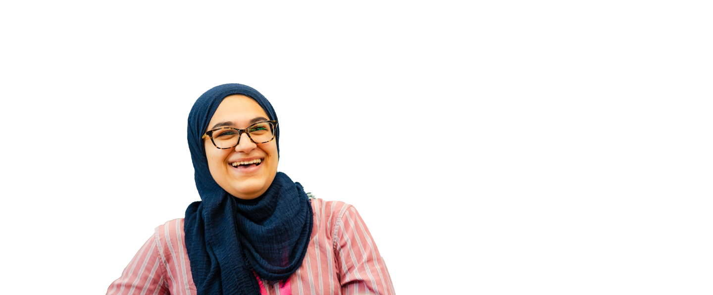 Woman in glasses wearing a pink striped shirt, seated and engaged.