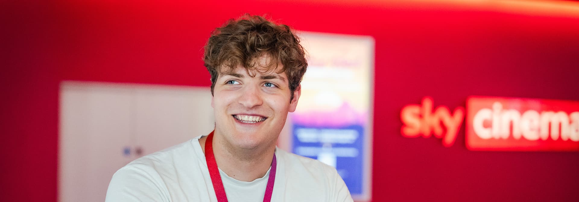 Smiling man in a white t-shirt in a Sky Cinema-branded area.
