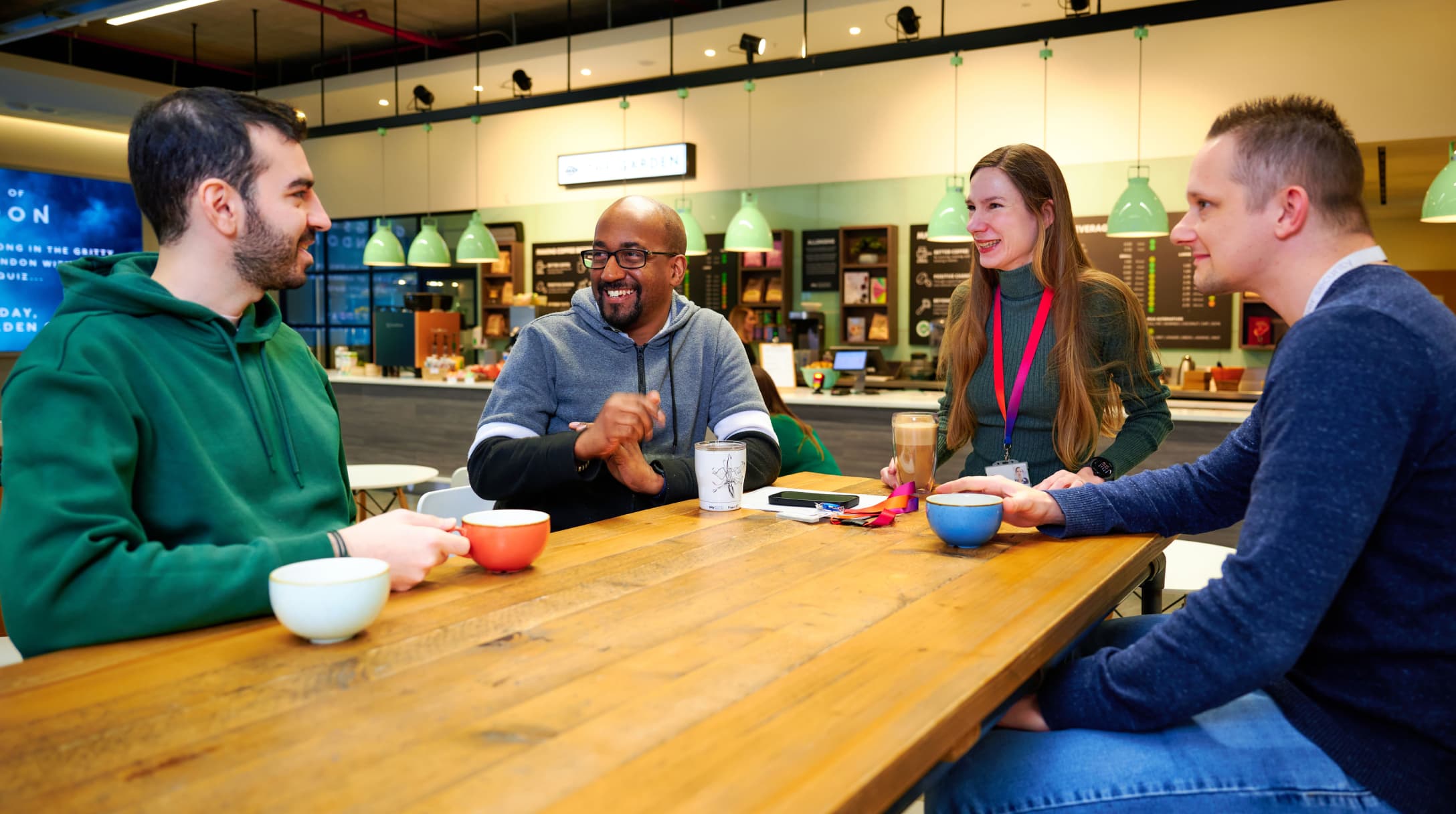 Group of colleagues drinking hot drinks and in conversation at a table