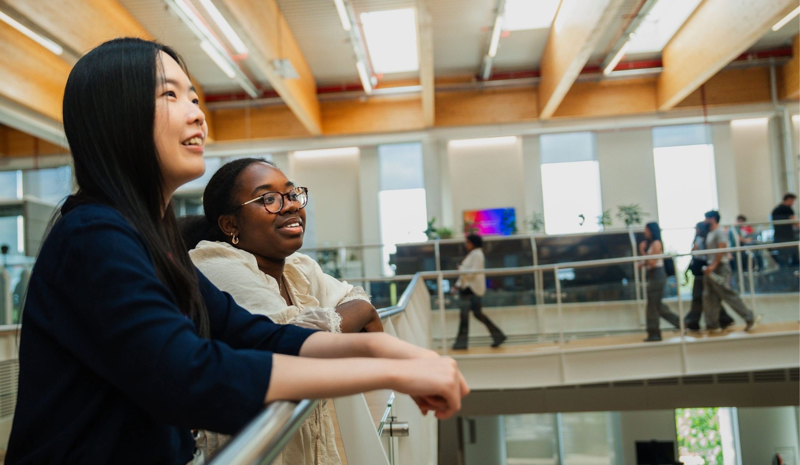 Three people leaning on a rail in a modern office