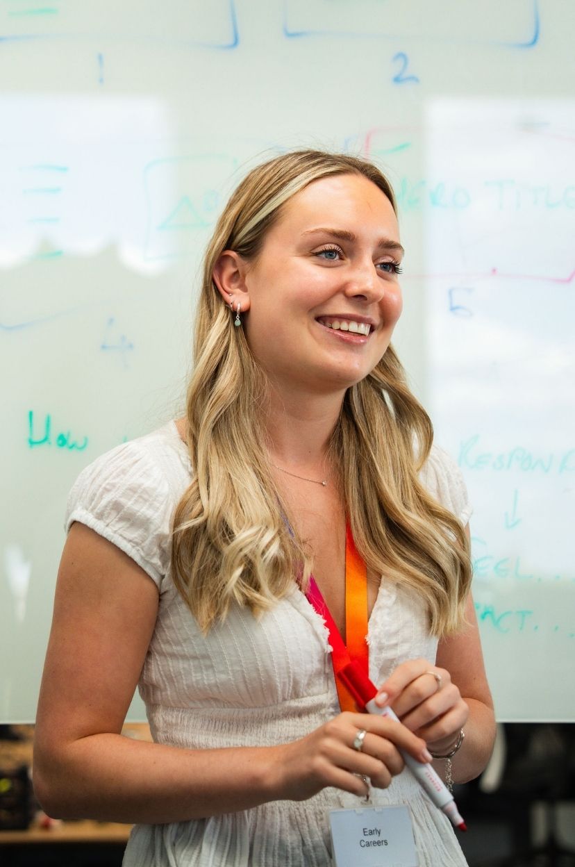 Woman in white shirt standing in front of a whiteboard