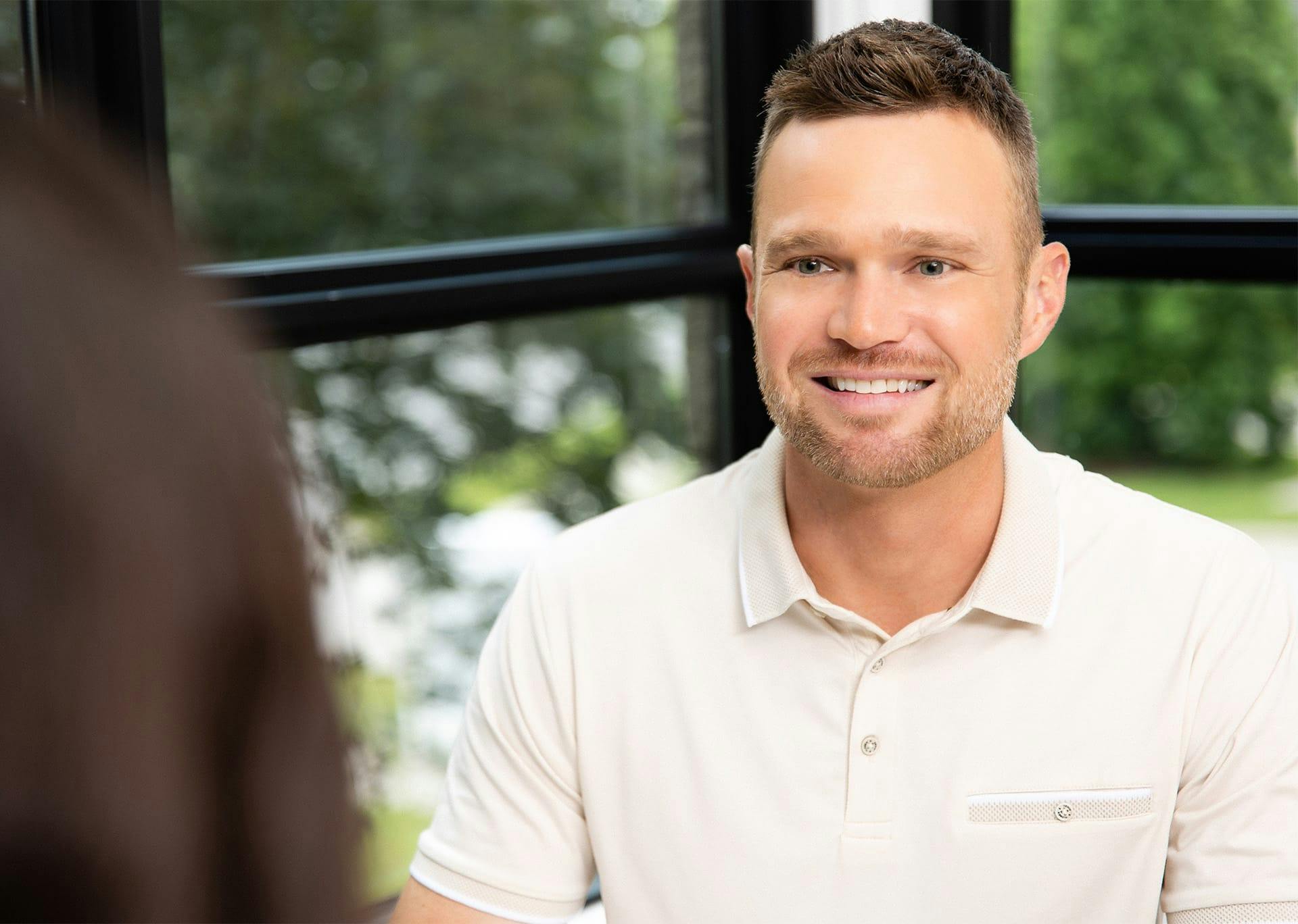 Man Smiling and look at someone sitting across from him