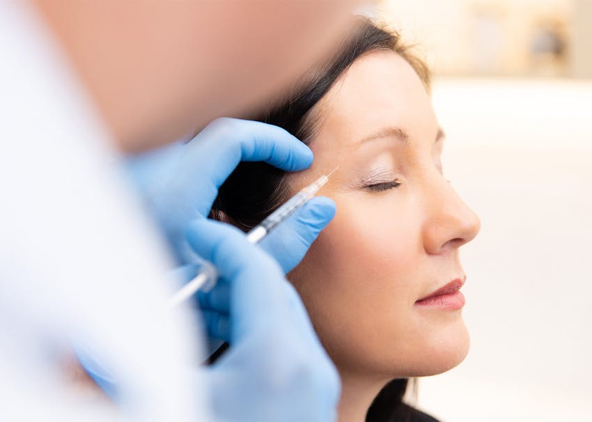Dr. Brace applying injectables to patient's eye brow