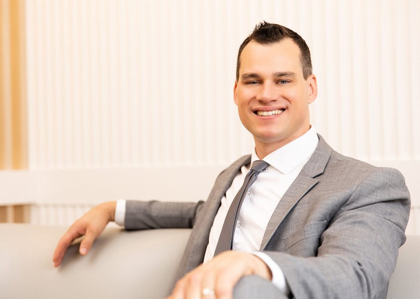 Dr. Brace Smiling with suit on sitting on couch