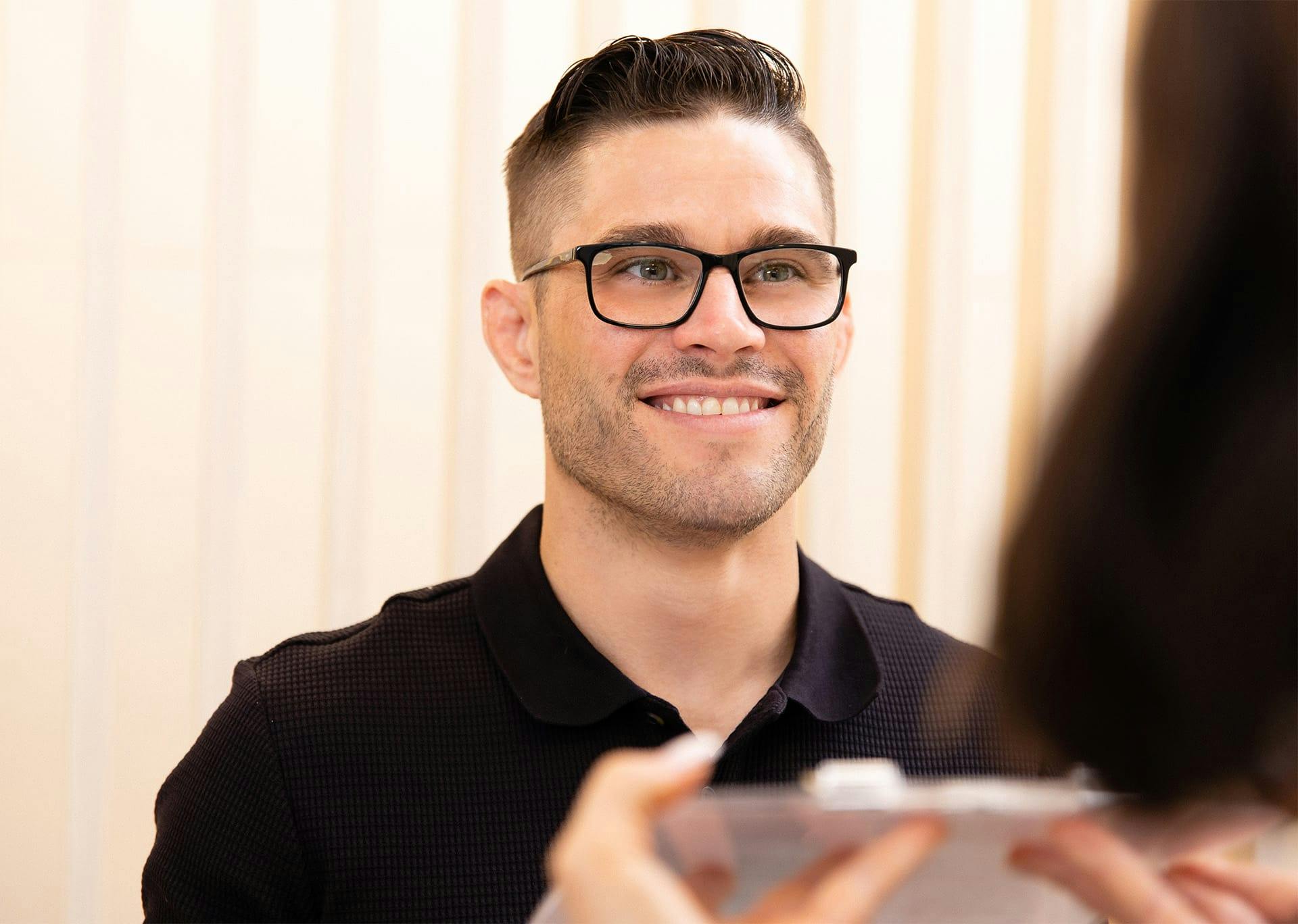 Receptionist helping smiling patient wearing glasses