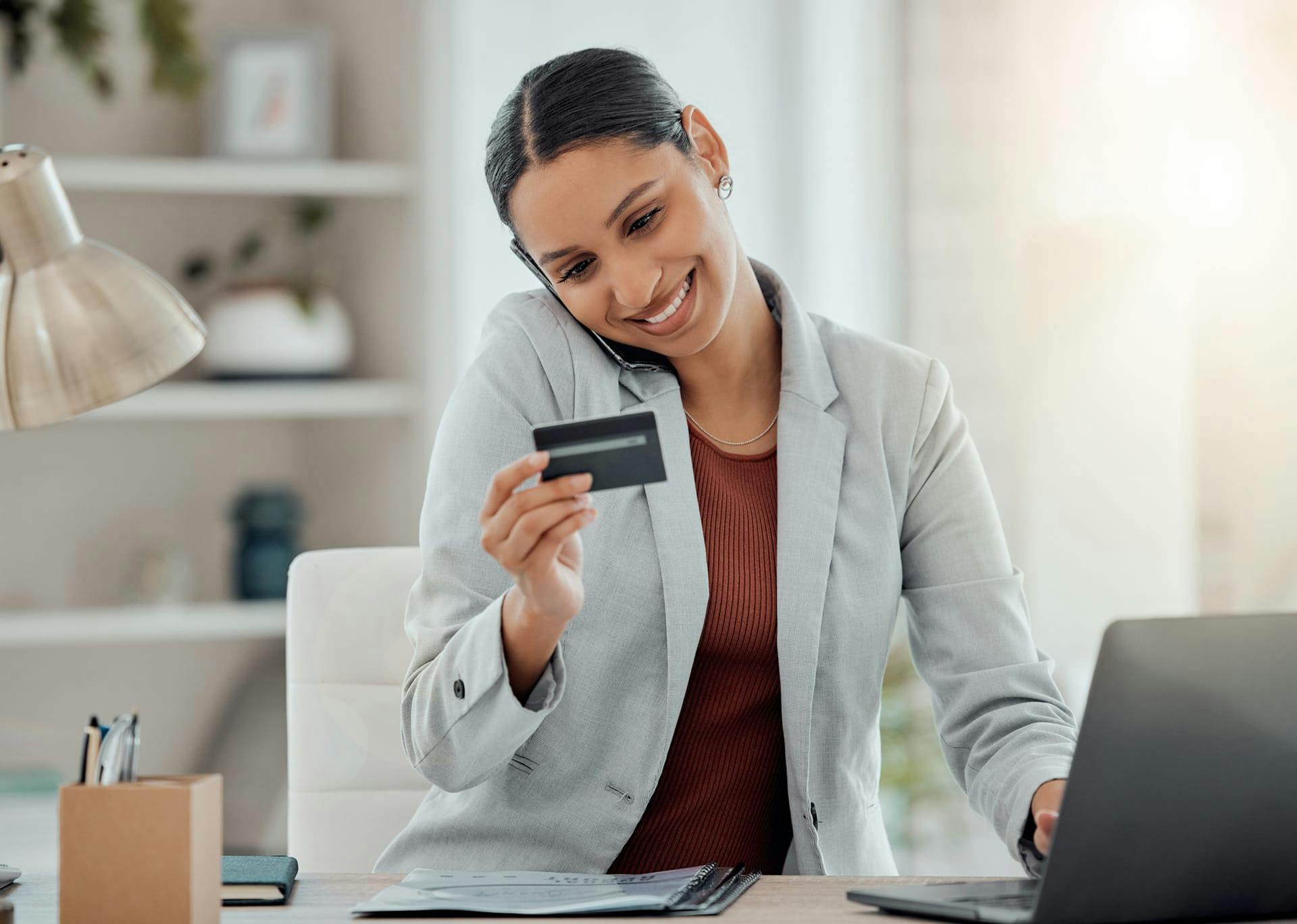 Woman smiling while on the phone looking at credit card