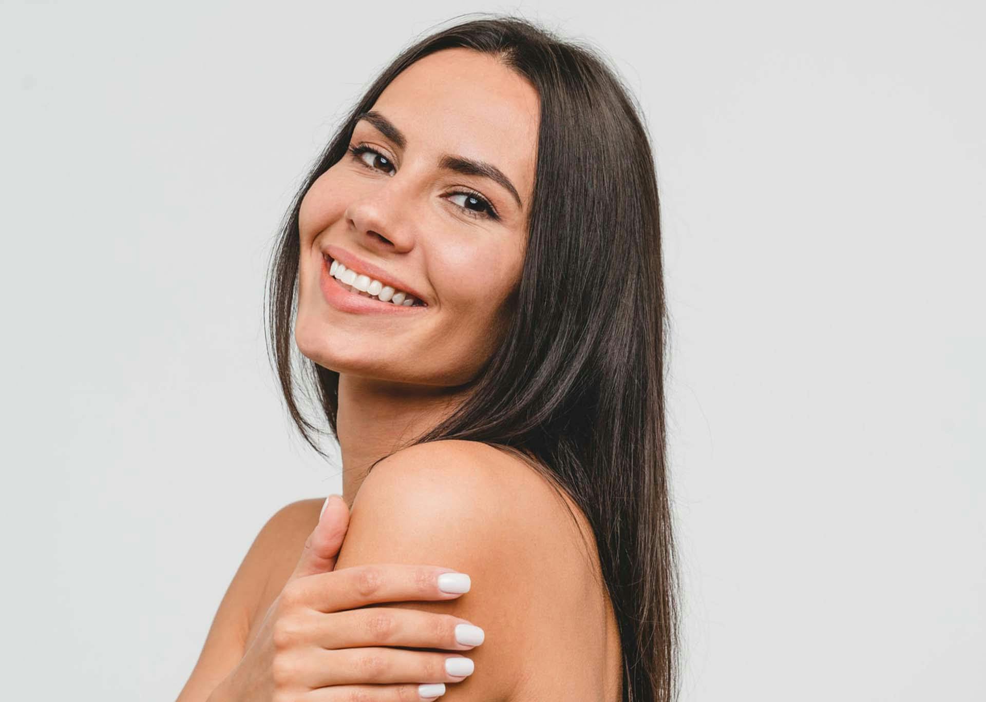 Model smiling and holding shoulder