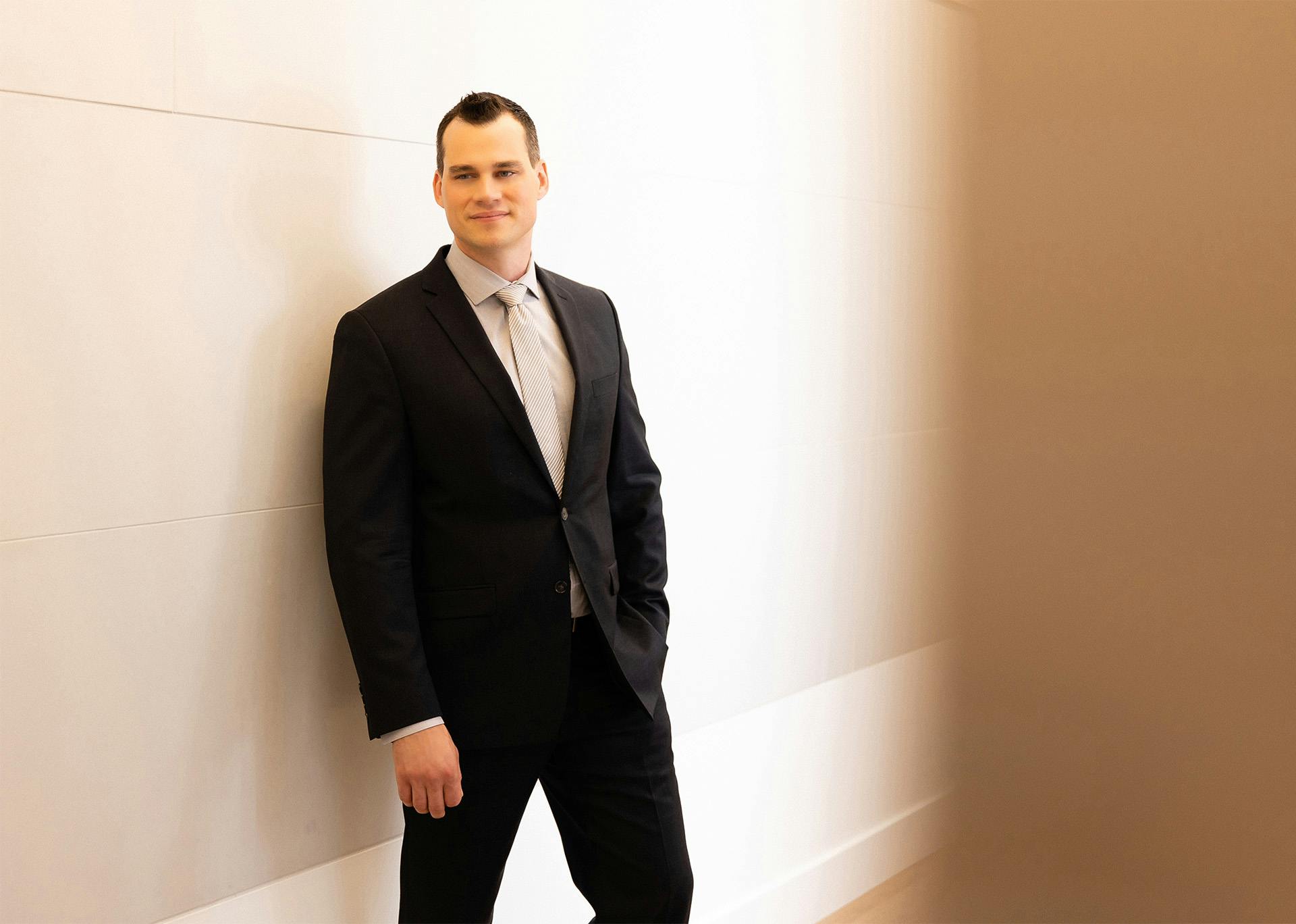 Dr. Brace in suit leaning against wall