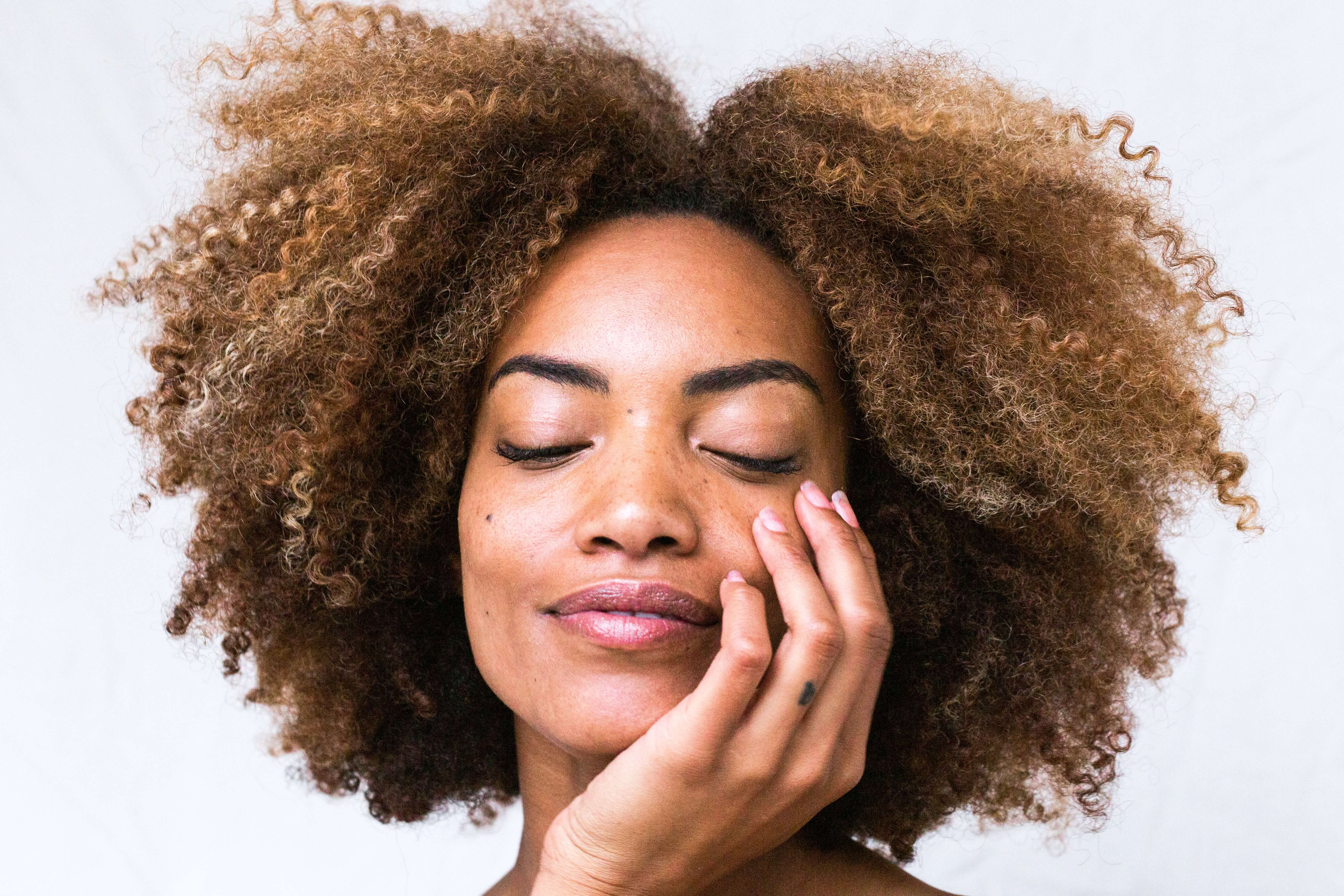 woman smiling with eyes closed holding her face