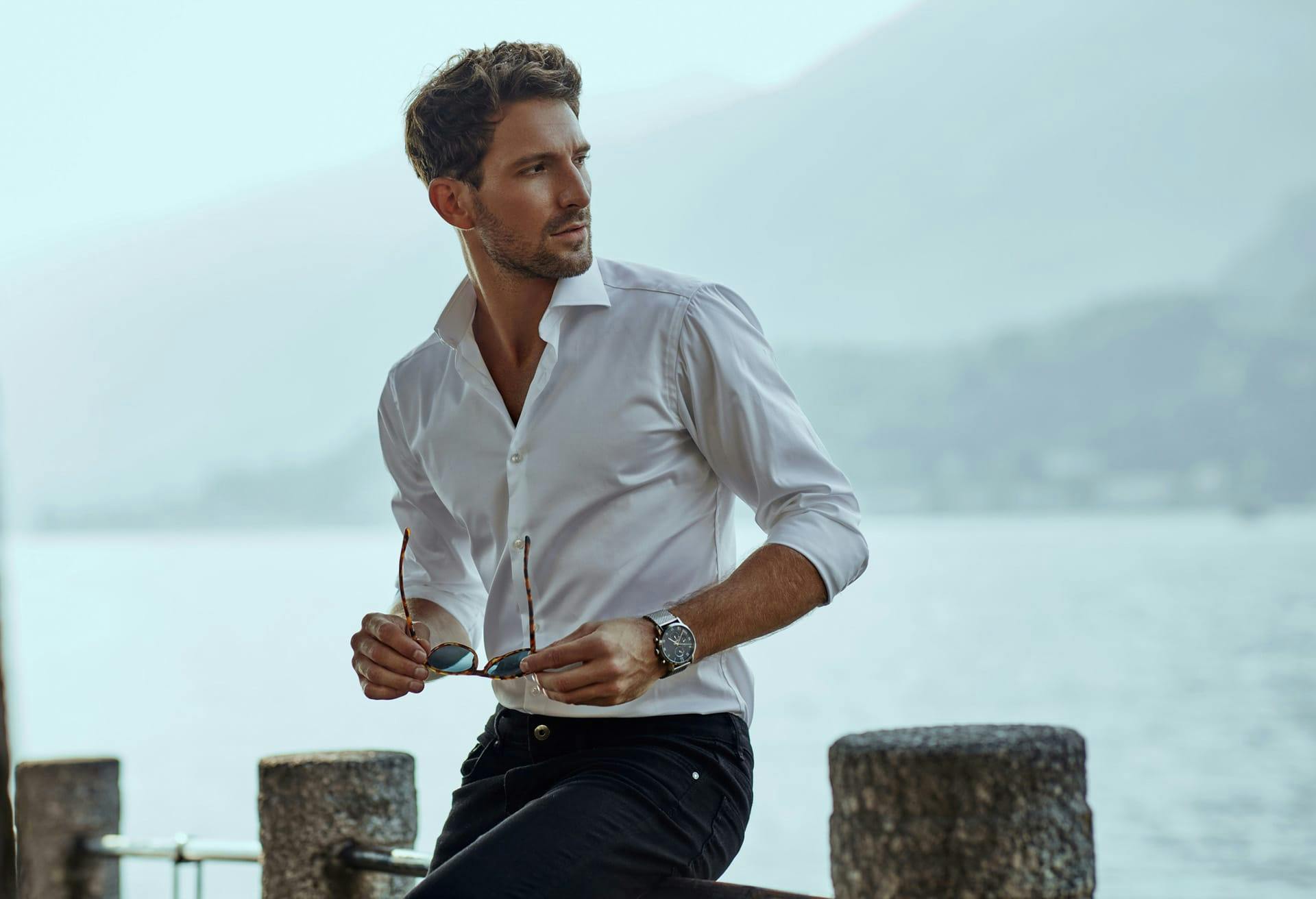 Man holding sunglasses sitting on railing