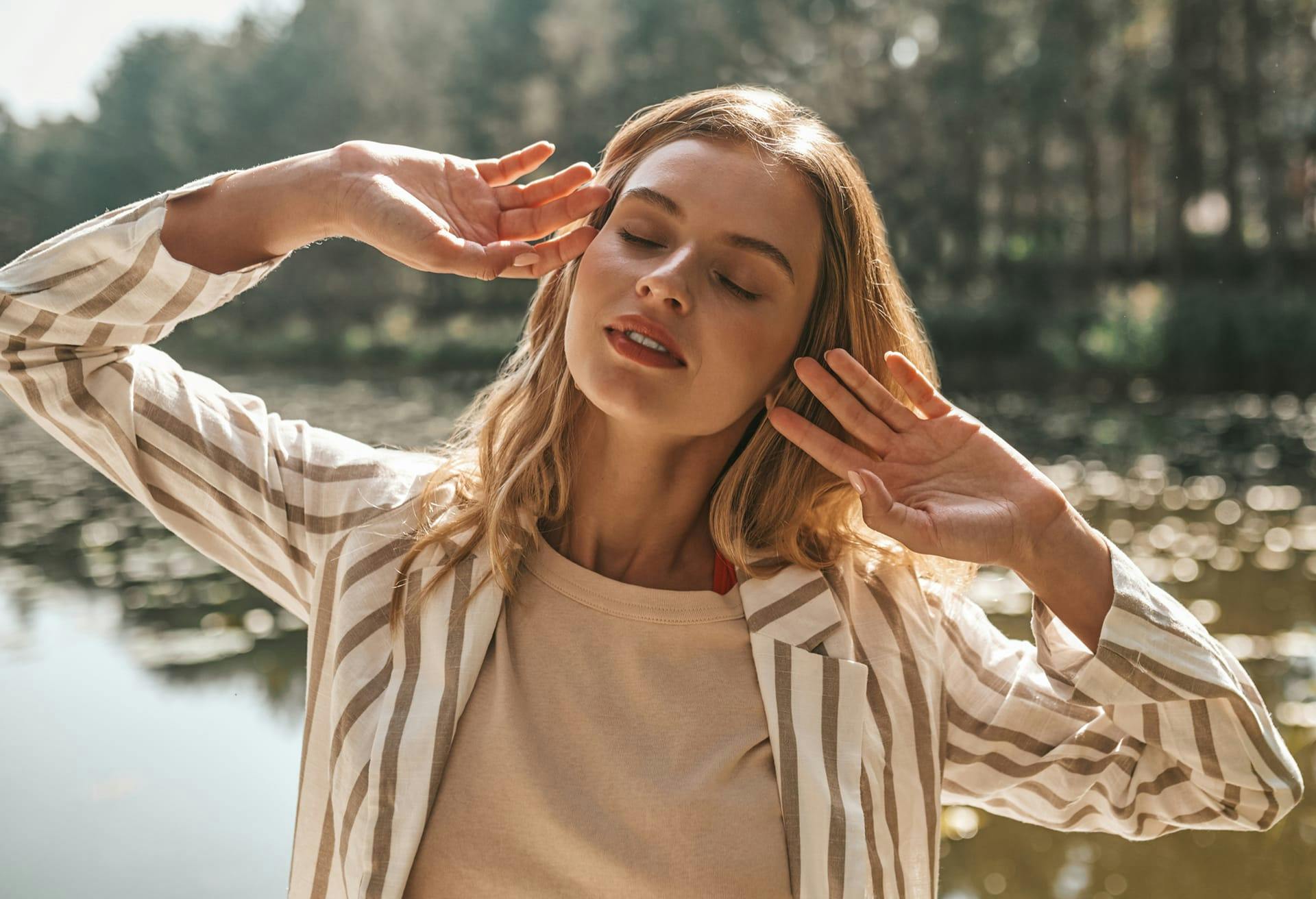 Woman vibing with eyes closed at the lake