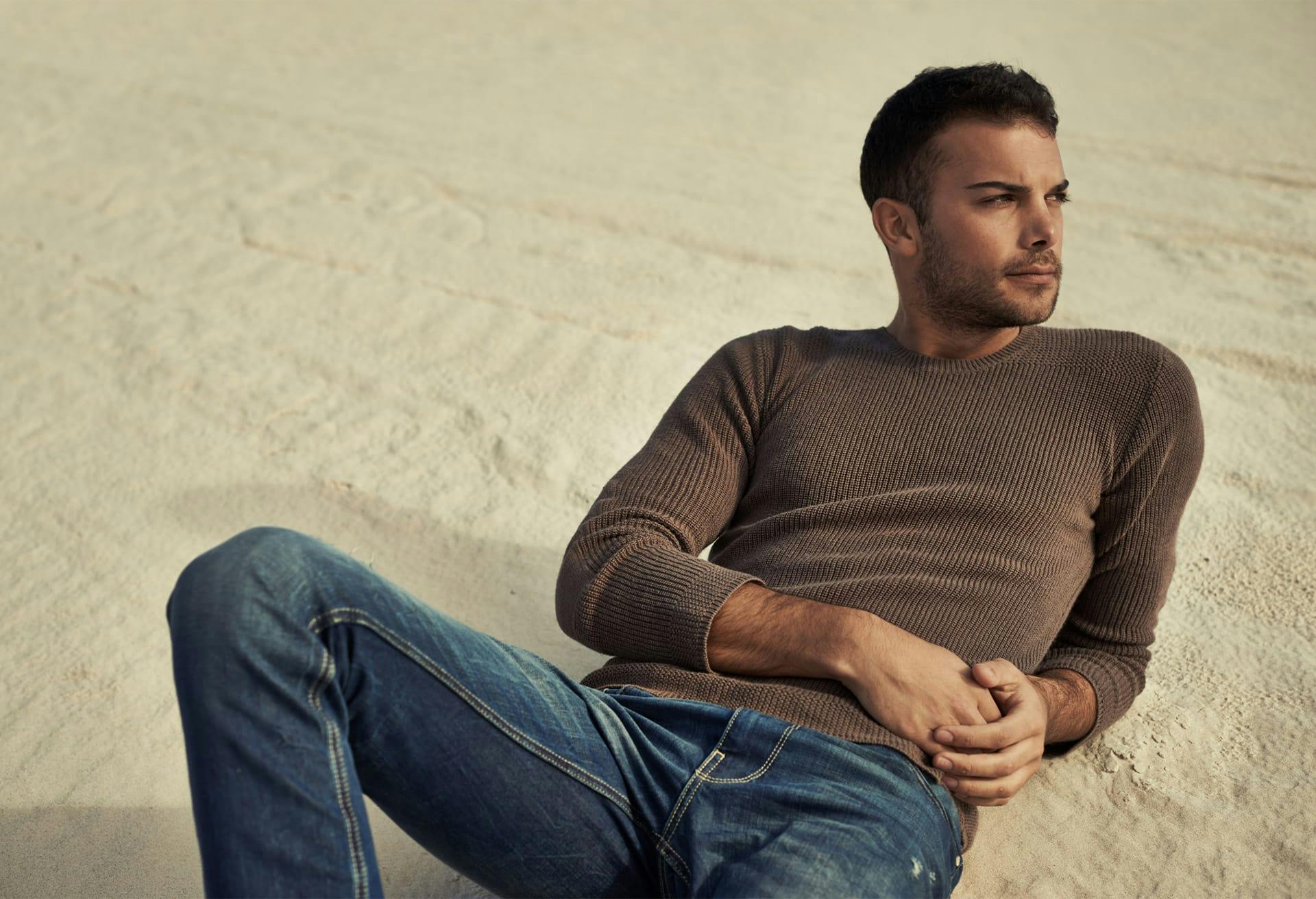 man wearing jeans laying down at the beach