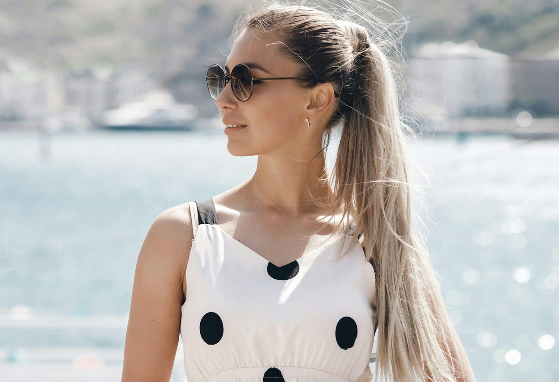 Woman smiling with sunglasses on next to lake