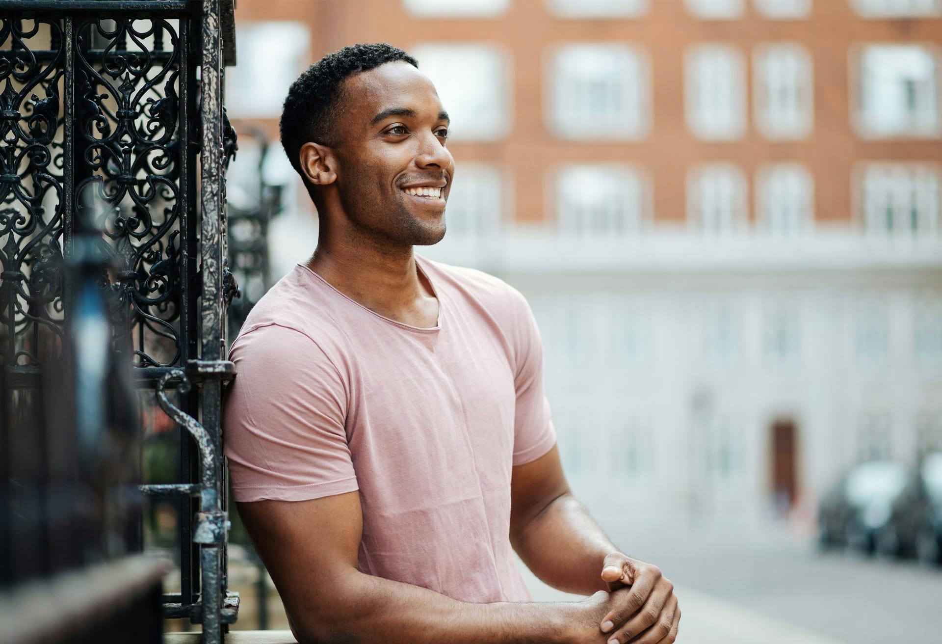 Man leaning against a railing on the sidewalk