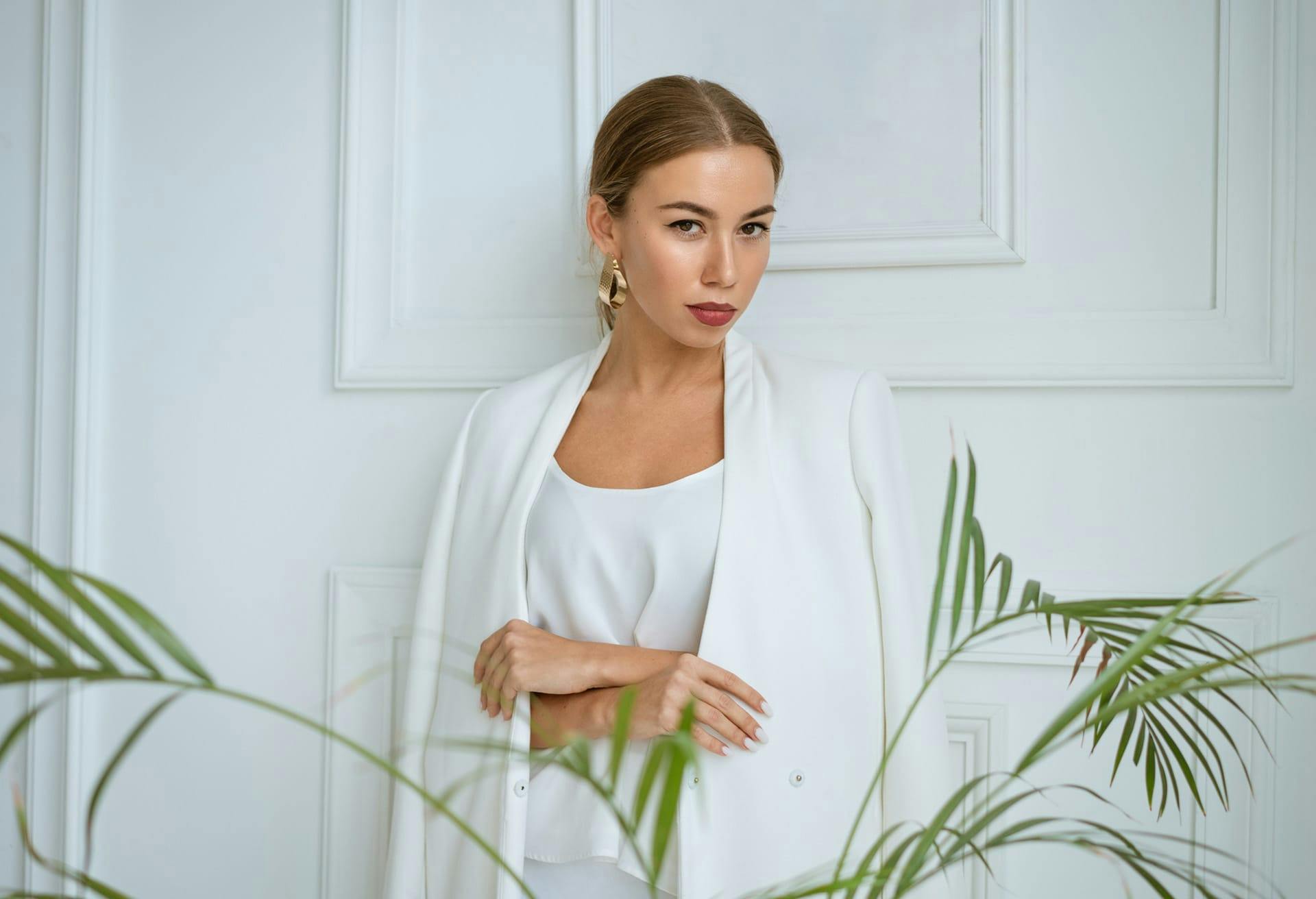 Woman wearing nice clothes standing behind a plant