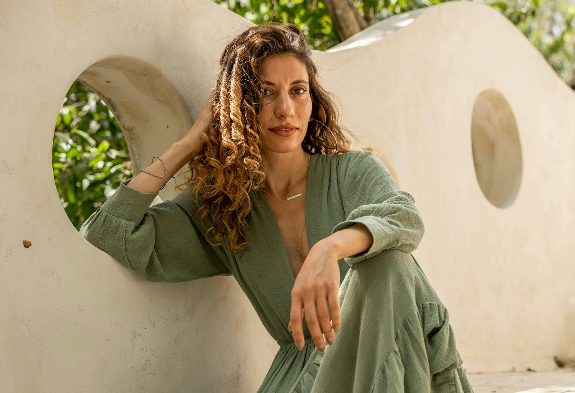 Woman with curly hair with her arm on her knee