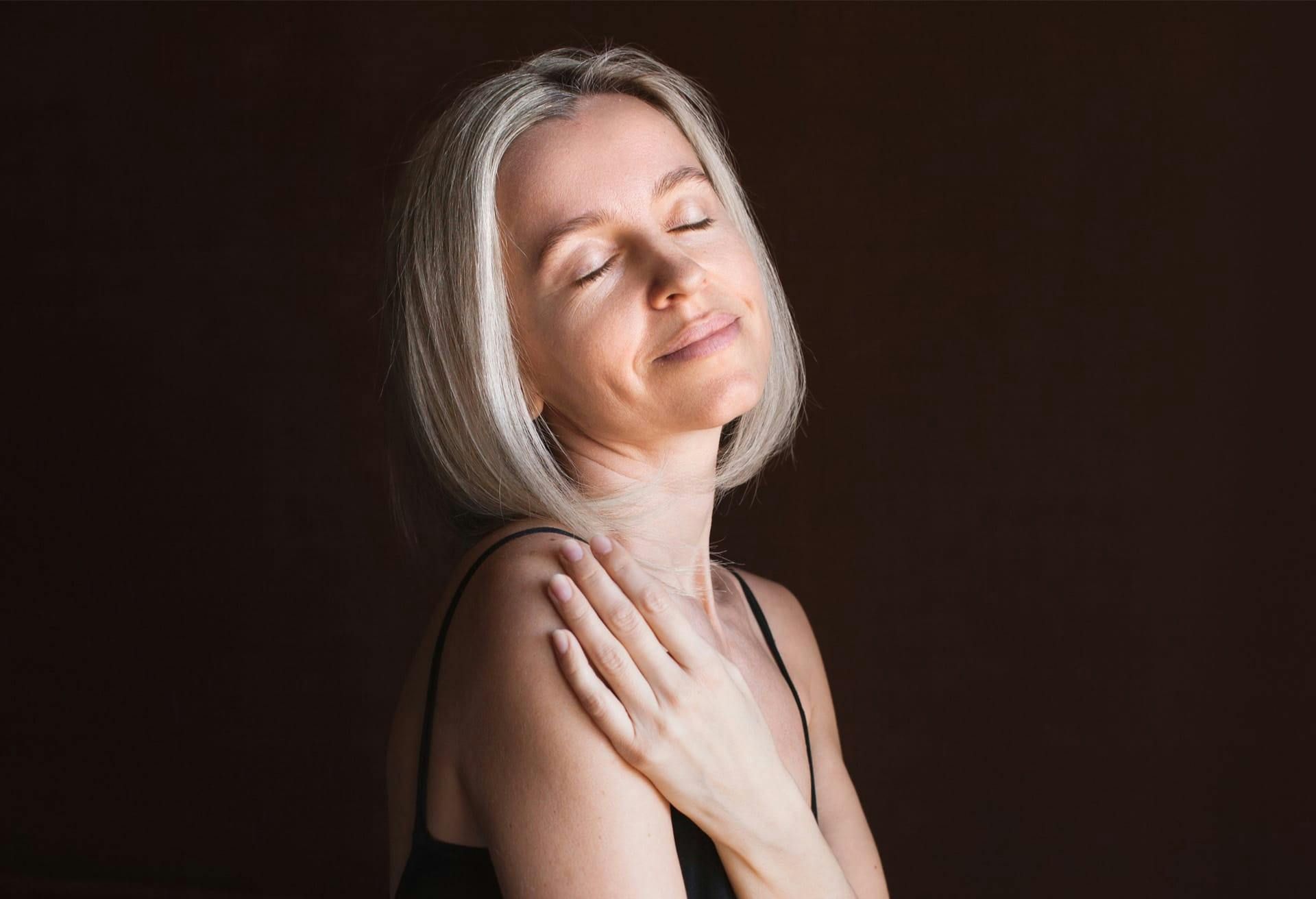 Woman with short grey/blonde hair with her eyes closed