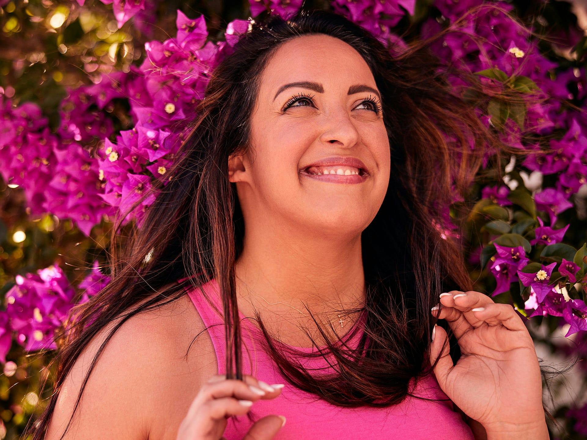 Woman smiling in front of pink flowers