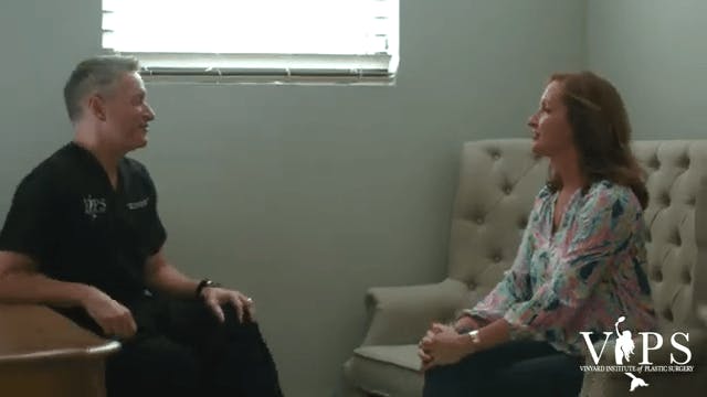 Dr. Vinyard speaking to a woman who is sitting on a couch.