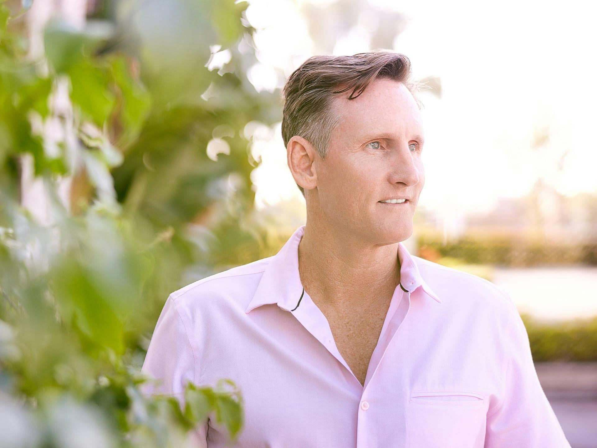 man in pink shirt near greenery