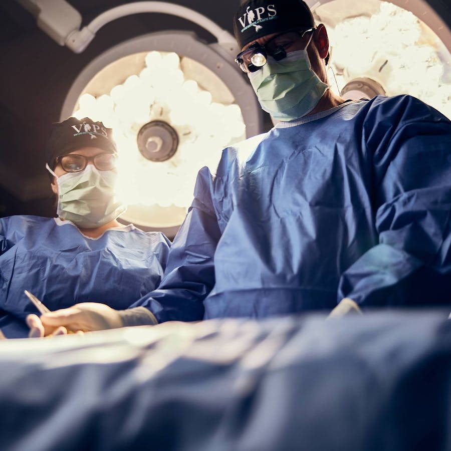 doctors in blue scrub suits and masks are operating in an operating room