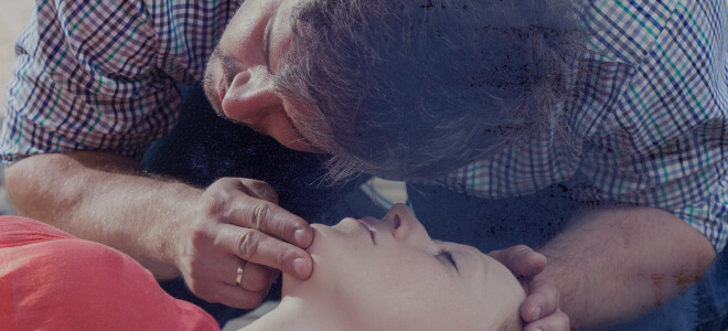 A man holding a person's chin to begin CPR.