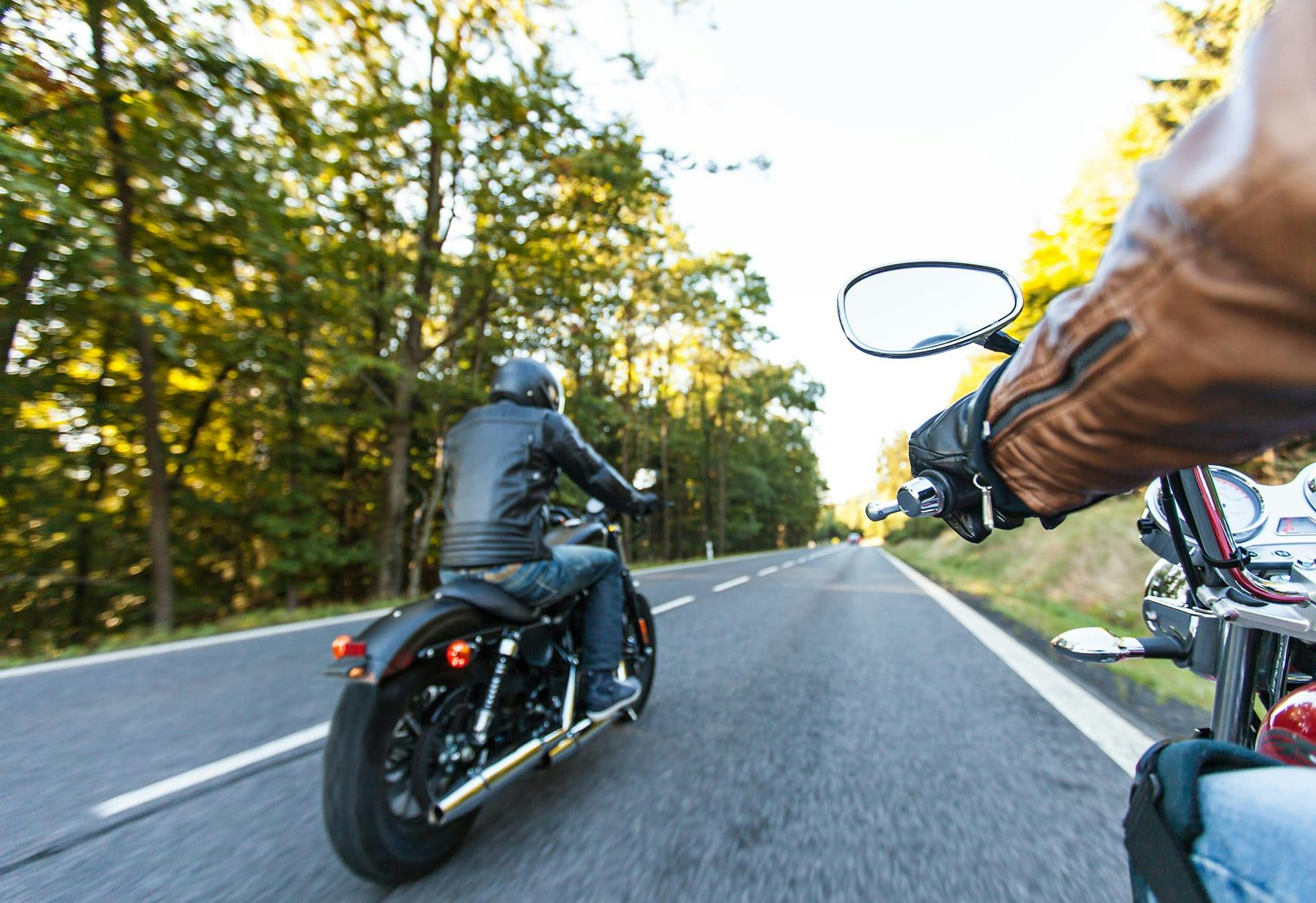 two men on motorcycles driving down road