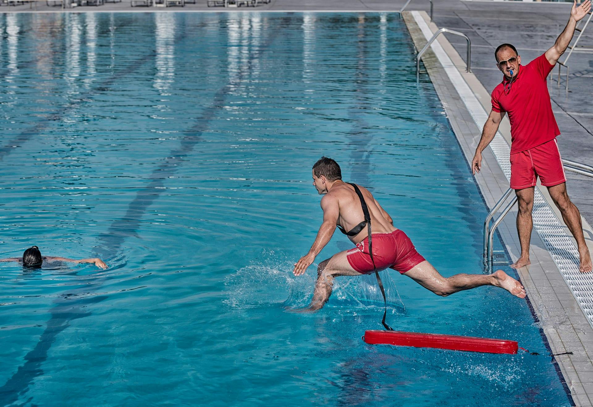 life guard jumping in pool to help drowning woman