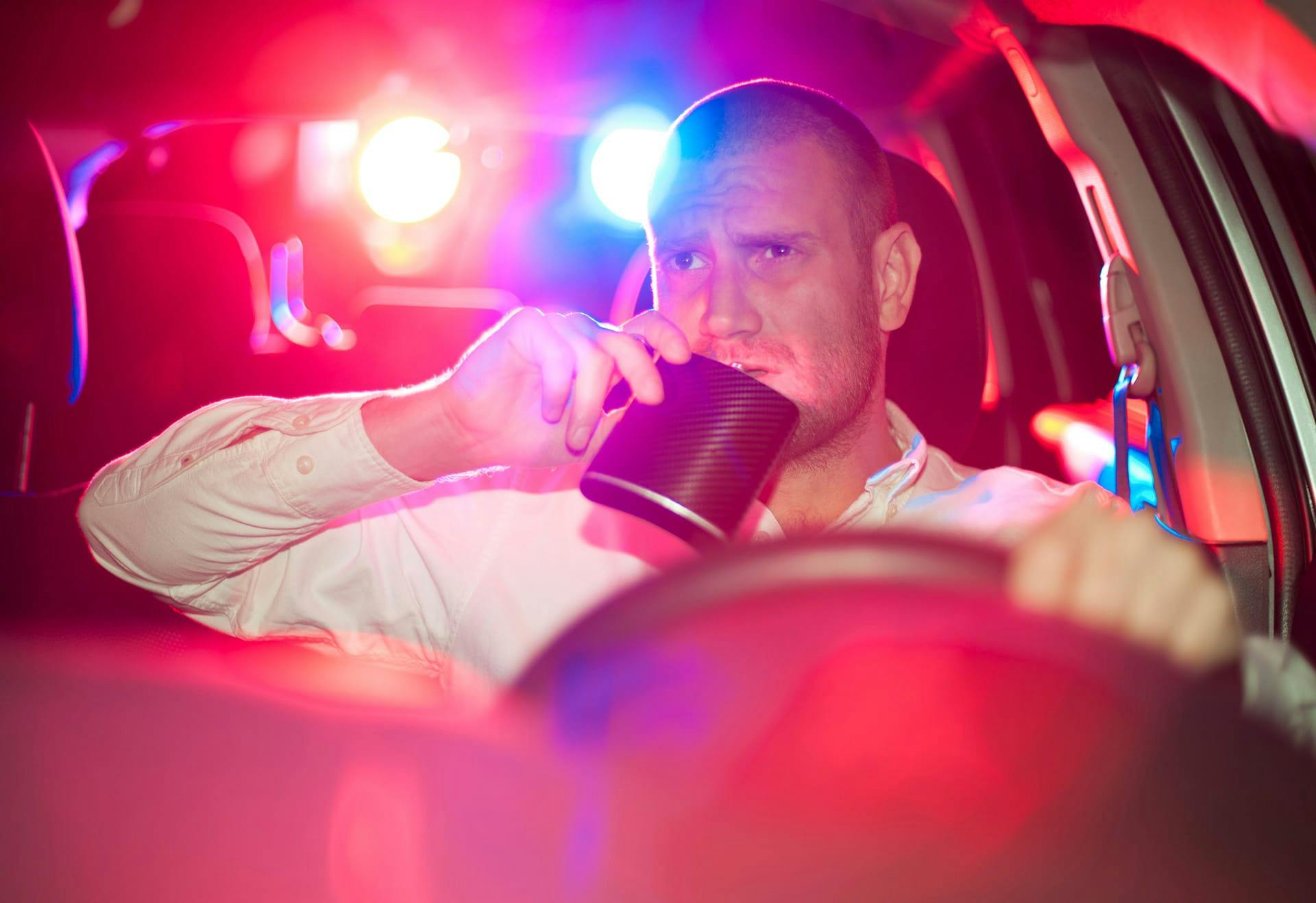 man drinking from flask while driving
