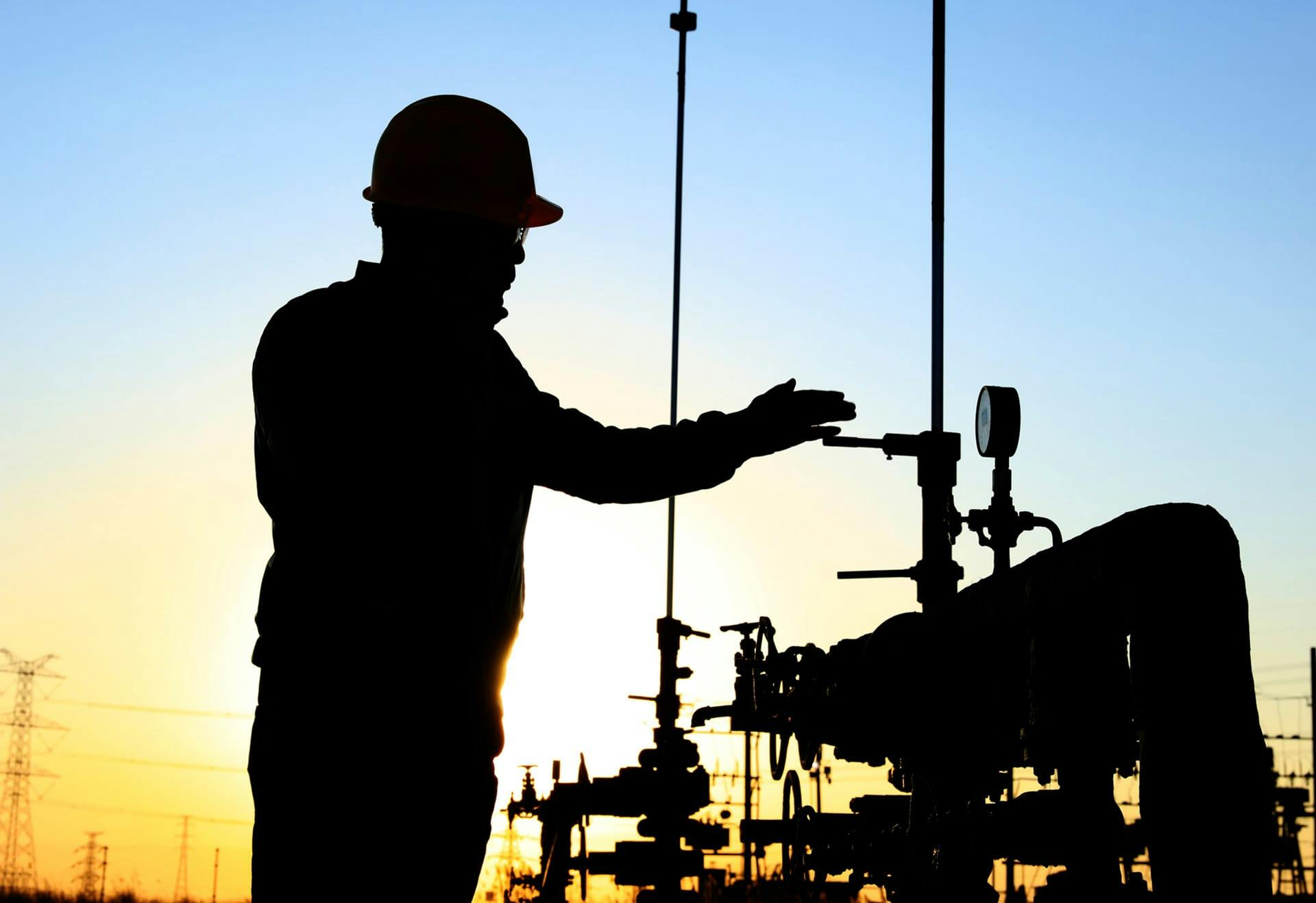 person working on oil derrick at sunset