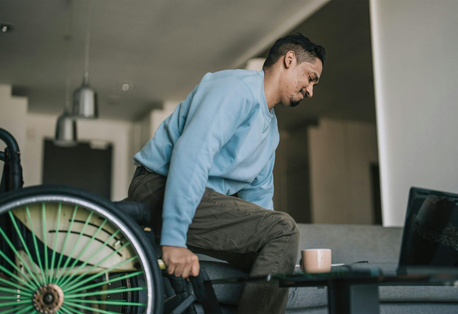 man in wheelchair moving to sit on couch