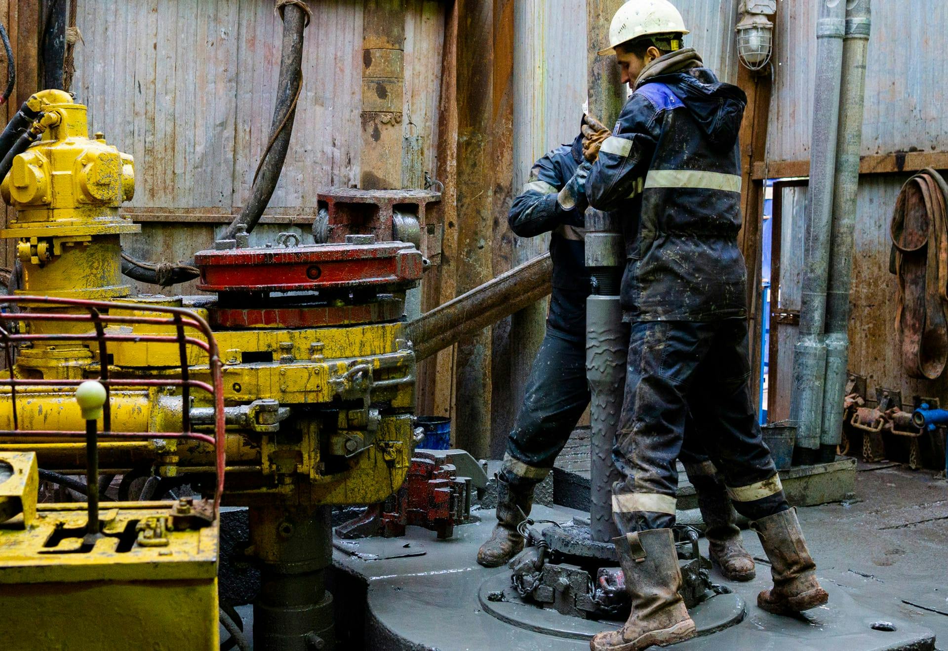 two people working on an oil pipe