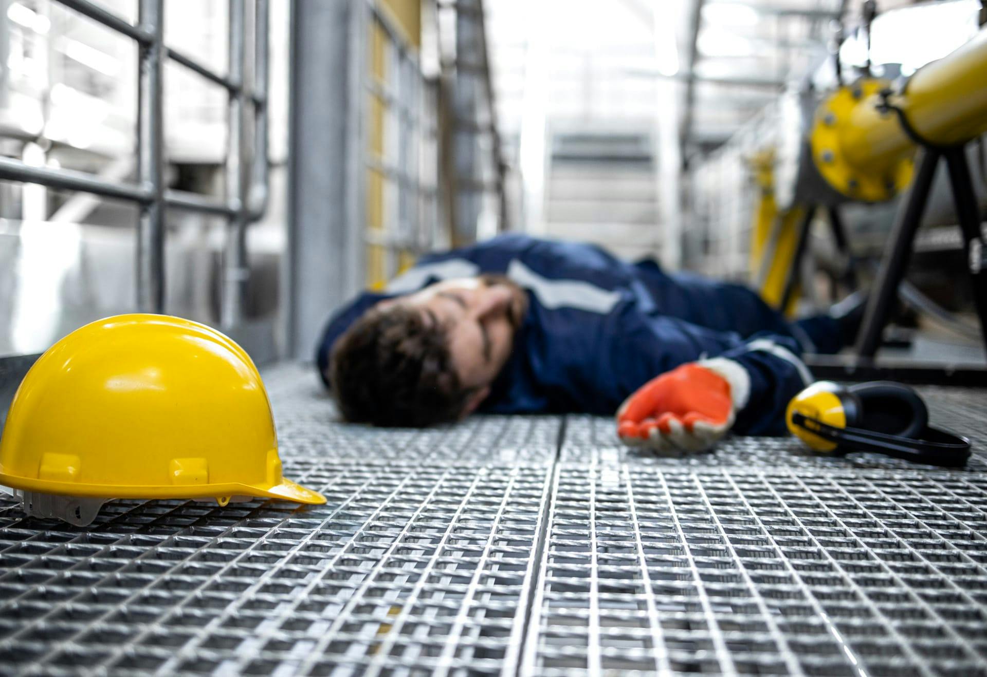 man lying unconscious next to hard hat